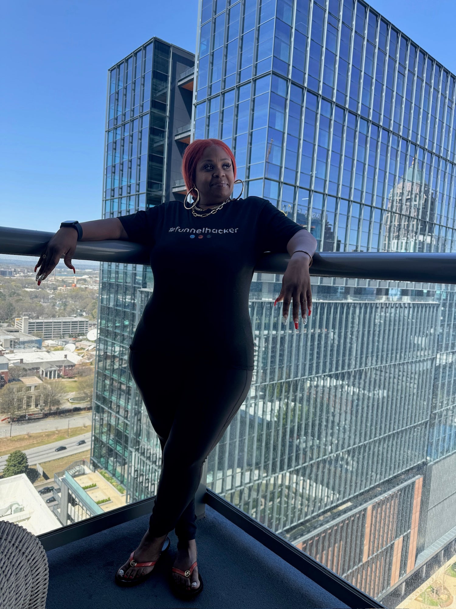 Founder wearing a black t-shirt with text, standing on a rooftop with a cityscape background